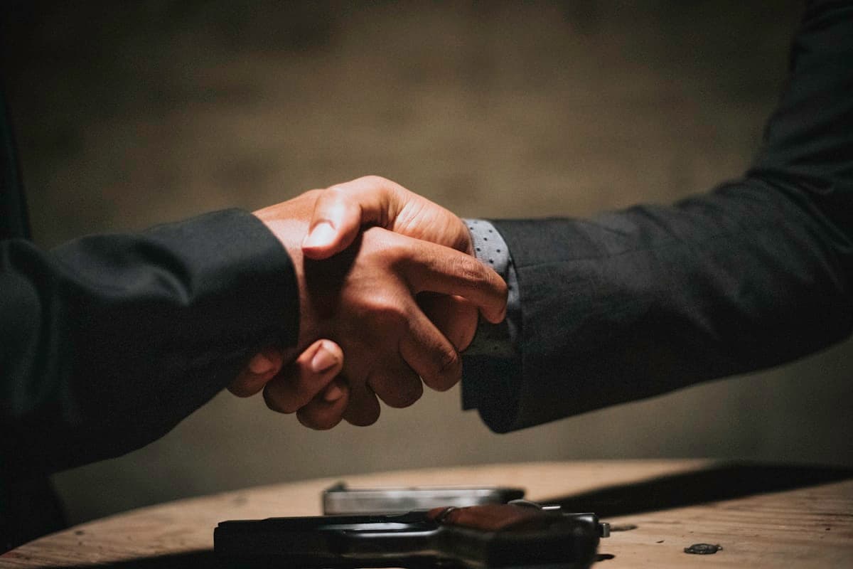 Two professionals shaking hands over a wooden table